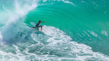 Local surfer riding big green wave at Padang Padang beach, Bali, Indonesia