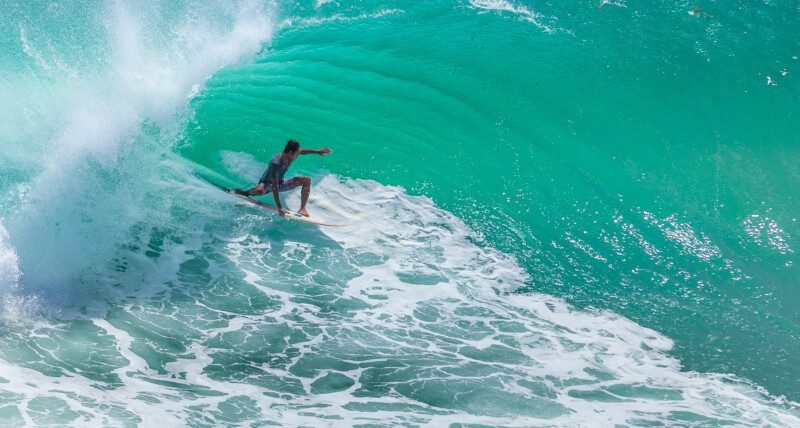 Local surfer riding big green wave at Padang Padang beach, Bali, Indonesia