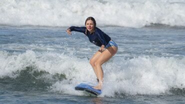 Beginner surfer girl on a surfboard at Berawa Beach, Bali