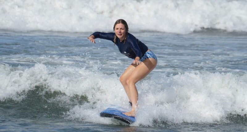 Beginner surfer girl on a surfboard at Berawa Beach, Bali